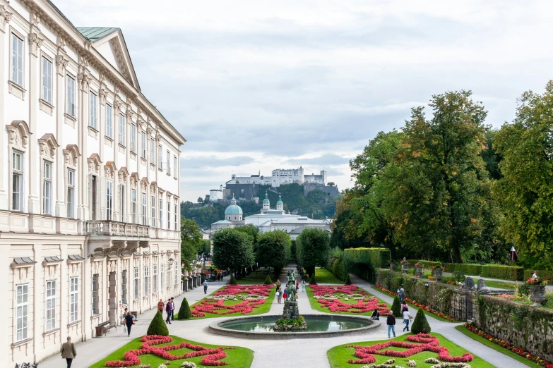 an elegant, formal garden with trees and shrubs on either side of a curved walkway