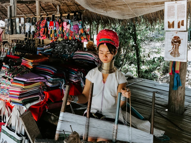 a woman sitting at an outdoor market holding a white basket