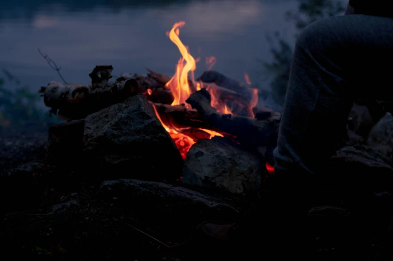 someone sitting next to a campfire at night