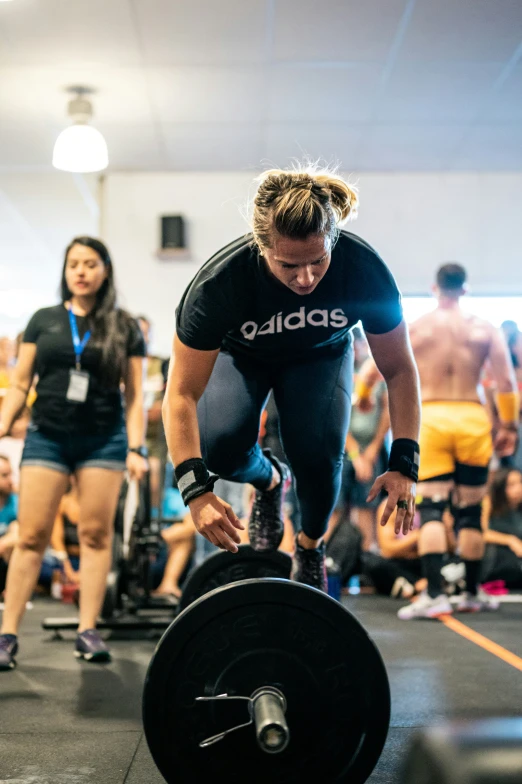 a woman in a black shirt is doing a squat with a bar