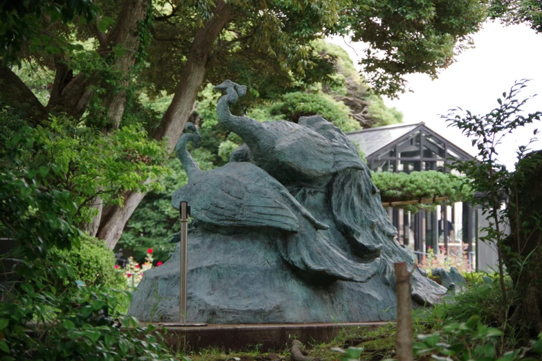 a statue is sitting in the grass near trees