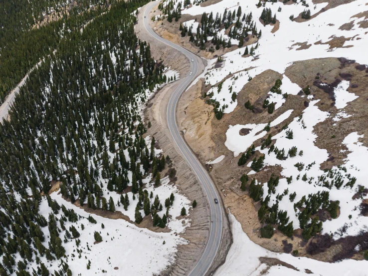 an aerial view of a curved roadway through a snowy mountain