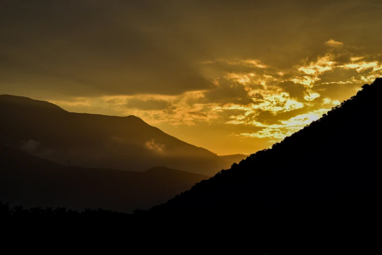 silhouette of a steep hill with the sun setting