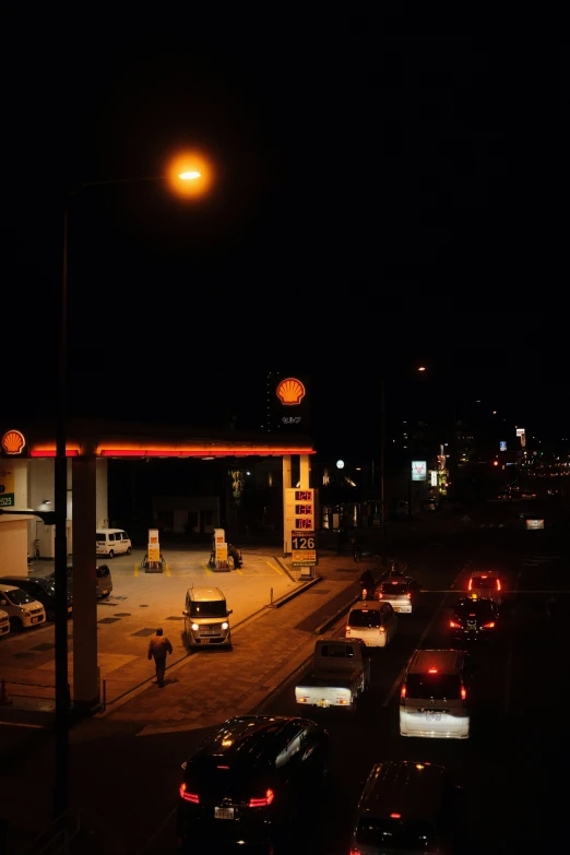 cars in the foreground at night near an oil station