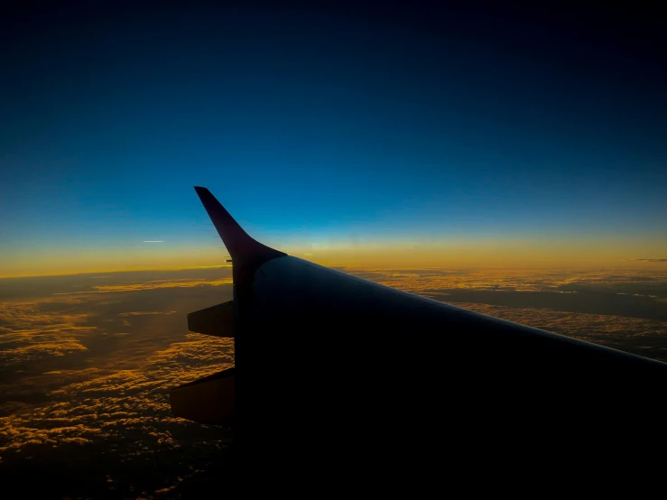 an airplane wing showing the light of the sunset