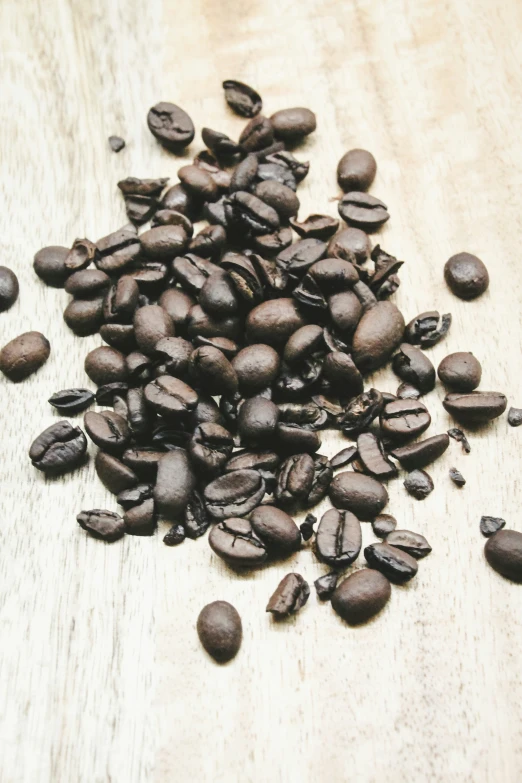 a pile of dark roasted coffee beans on a wooden surface