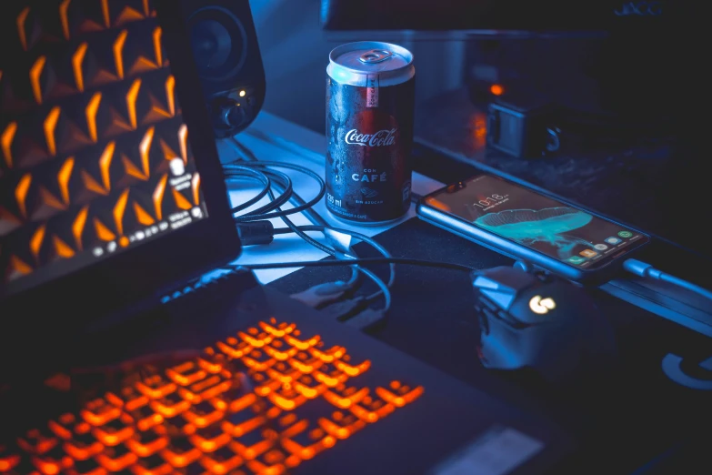 a beer can sitting next to a cellphone and computer keyboard