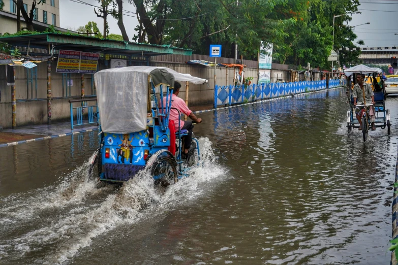 people riding bikes and a rickshaw driving down the street