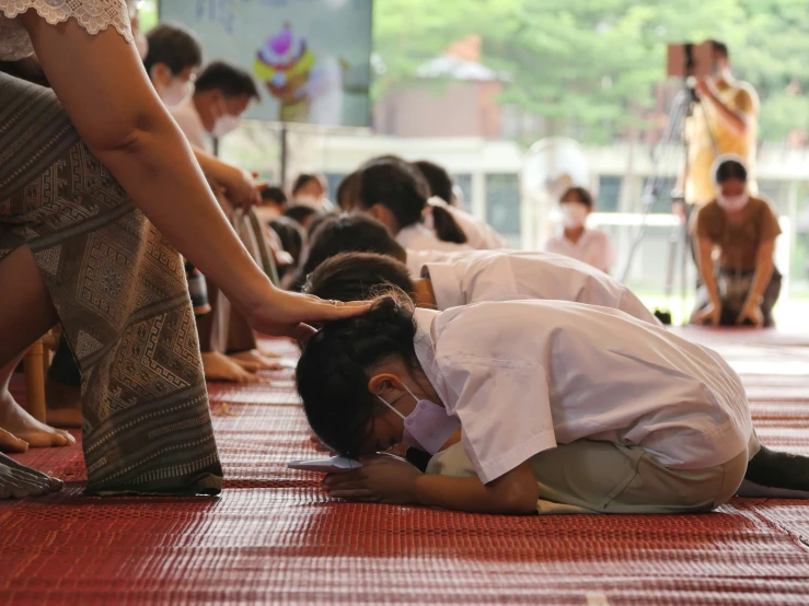 an asian man wearing white kneeling on the ground