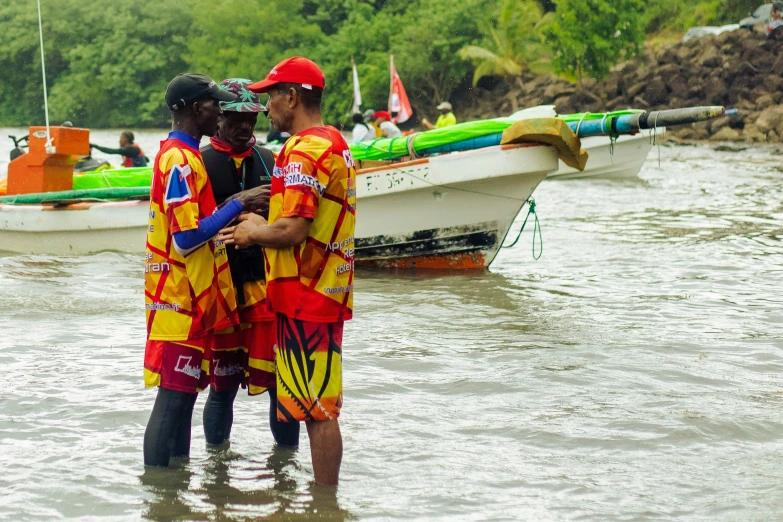 two men in life jackets standing near boats