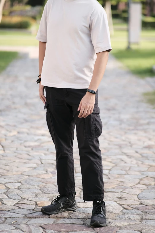 man in a white shirt, black pants and hat on cobblestones