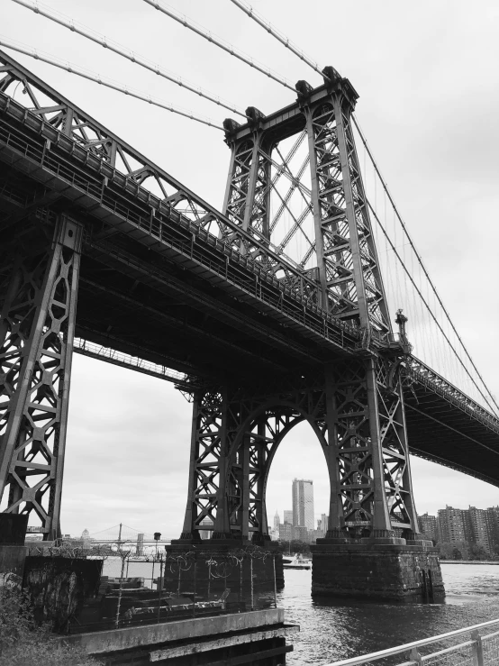 the brooklyn bridge from a nearby river on a cloudy day