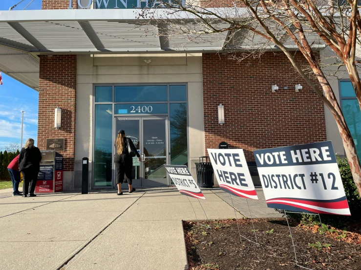 voting day signs sitting on the side of a brick building