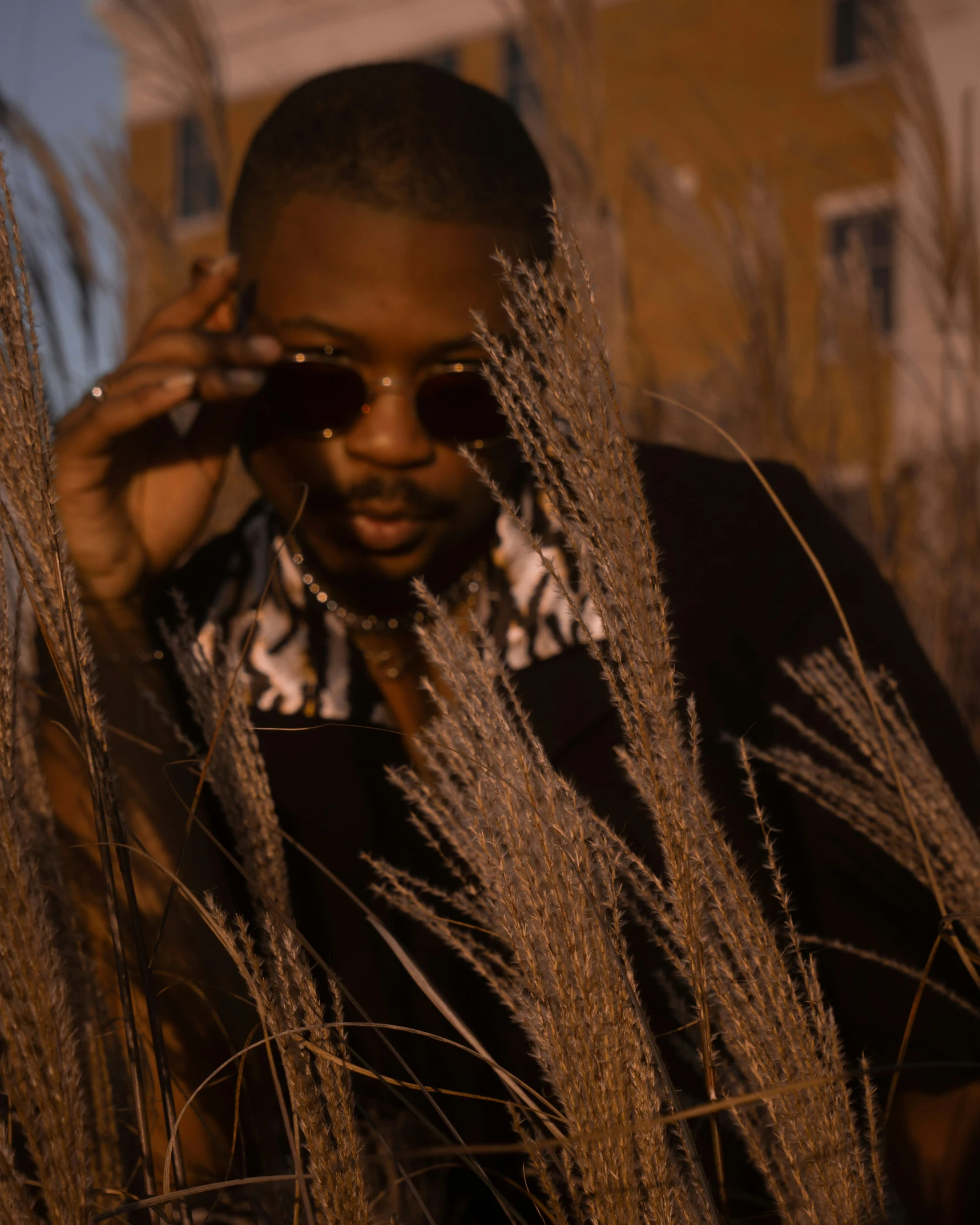 young black man holding cellphone and looking through weeds