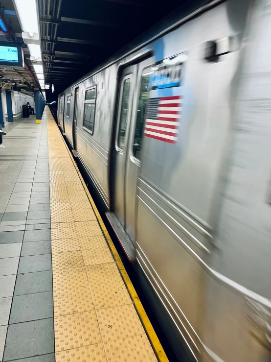 a silver subway train arriving at a train station