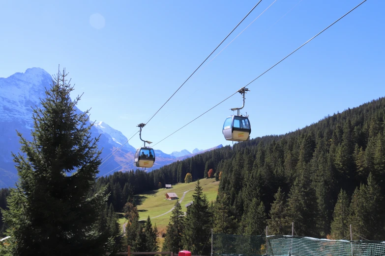 two people ride up a ski lift on a sunny day