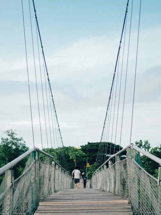 two people walking on a bridge over a body of water