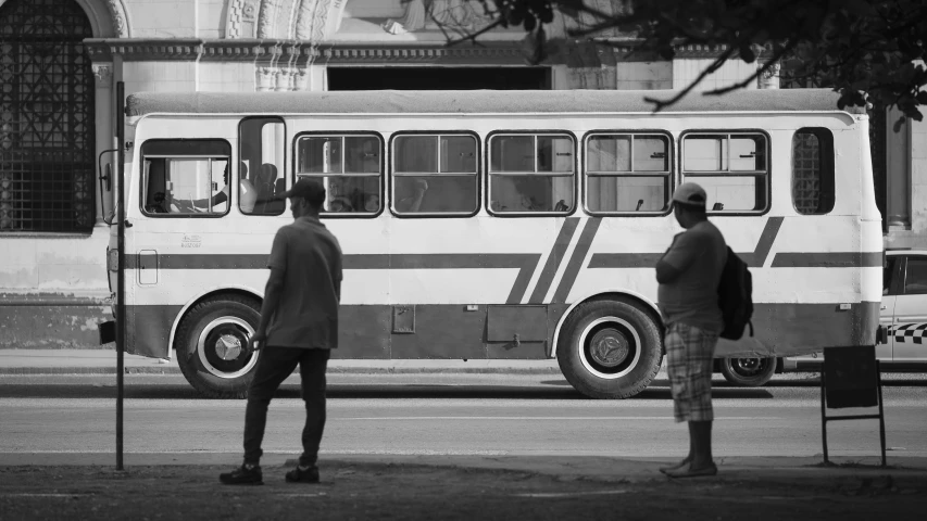 a couple of men are standing outside a bus