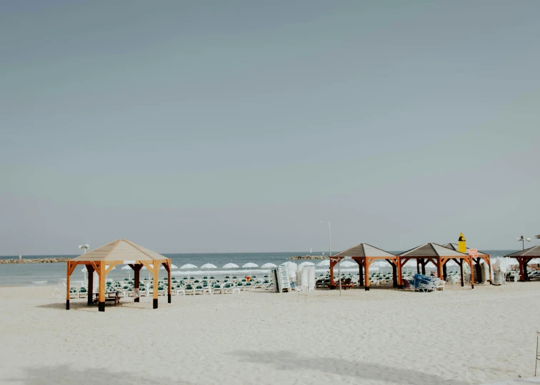 a row of umbrellas at the beach with a person sitting on a chair