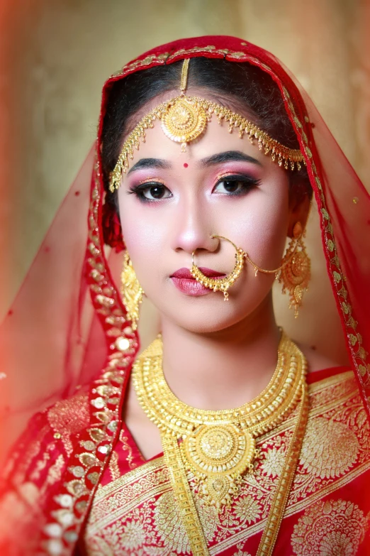 a woman in red and gold dress with veil over her face