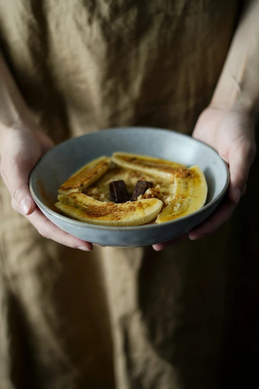 a white bowl of food being held by a person