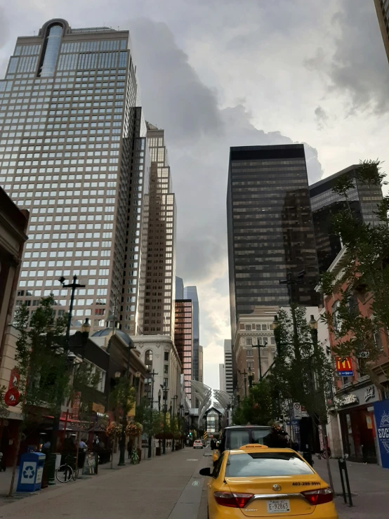 yellow taxi cab on street next to tall buildings