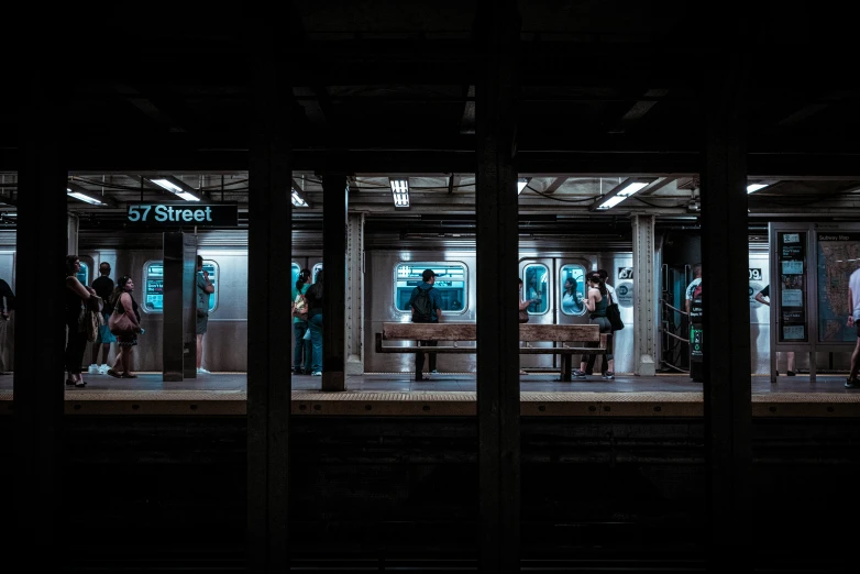 a group of people stand in a subway station waiting for the train