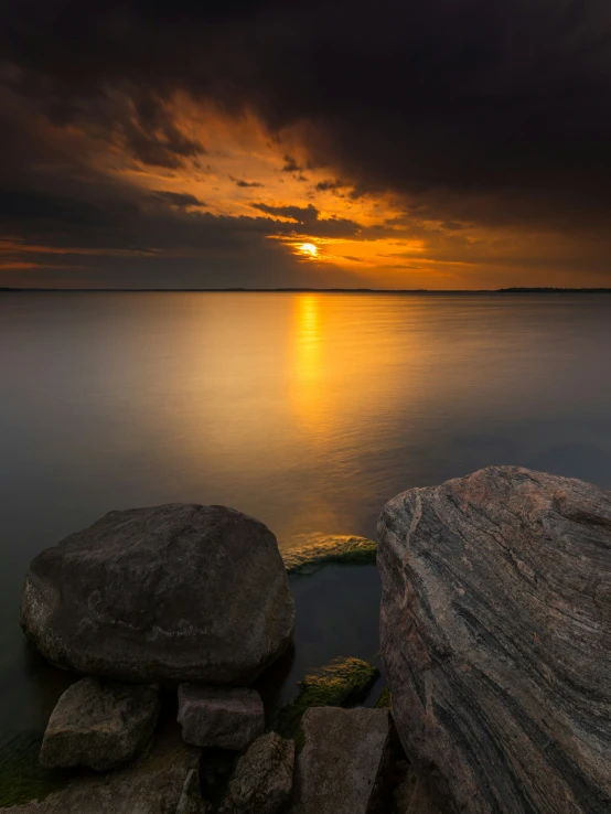 the sunset is shining on some rocks in the water