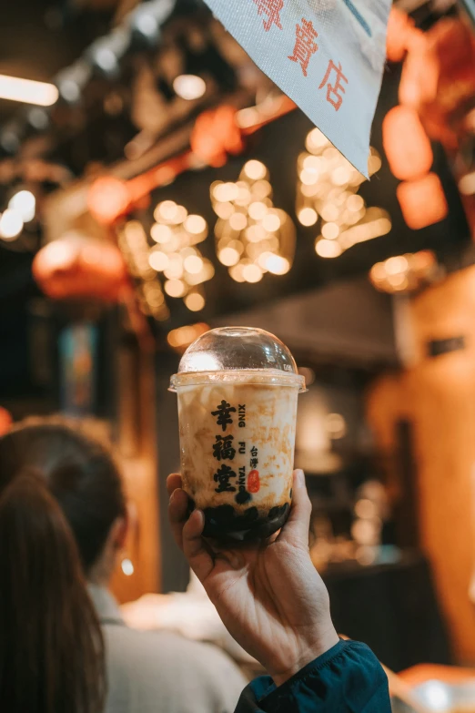 a person is holding a cup filled with ice cream and other food