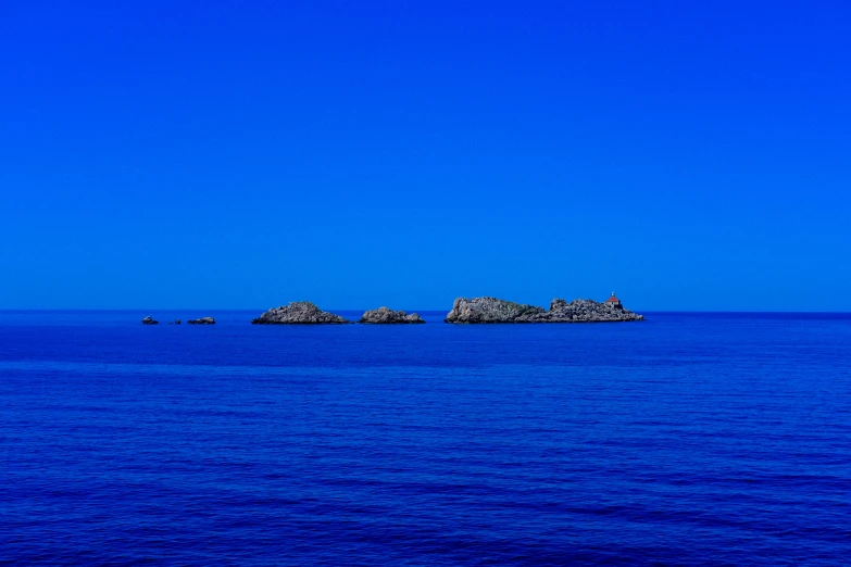 small island surrounded by a group of rocks in the ocean