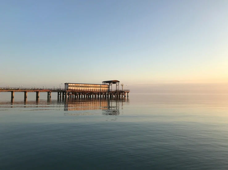 a pier with the ocean in front of it with a building on the water