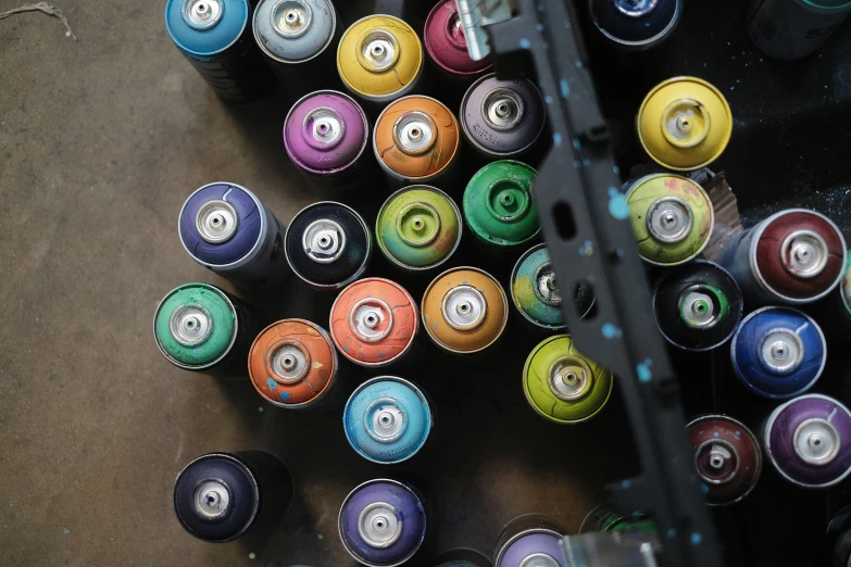 an overhead s of multiple multicolored cans next to a silver cart