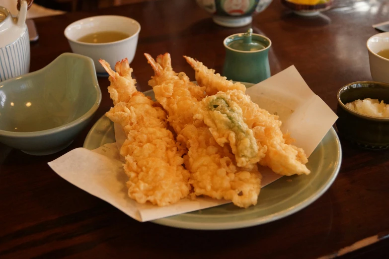 some fried food is sitting on a plate next to small cups