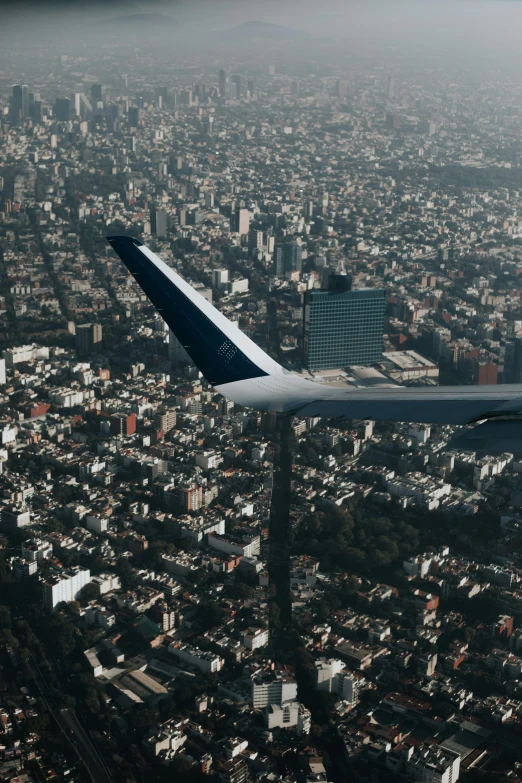 the wing of a commercial airplane as it flies over an urban area