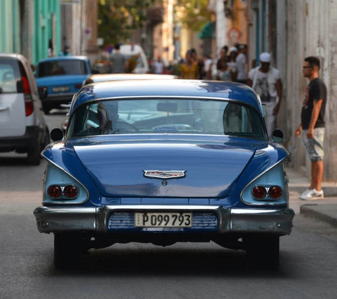 a vintage blue car is parked in front of a man