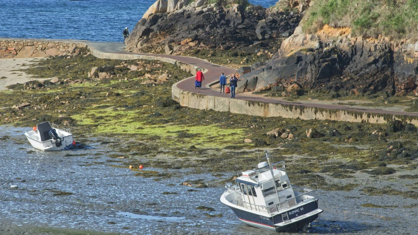 a white boat sitting next to a rocky shore