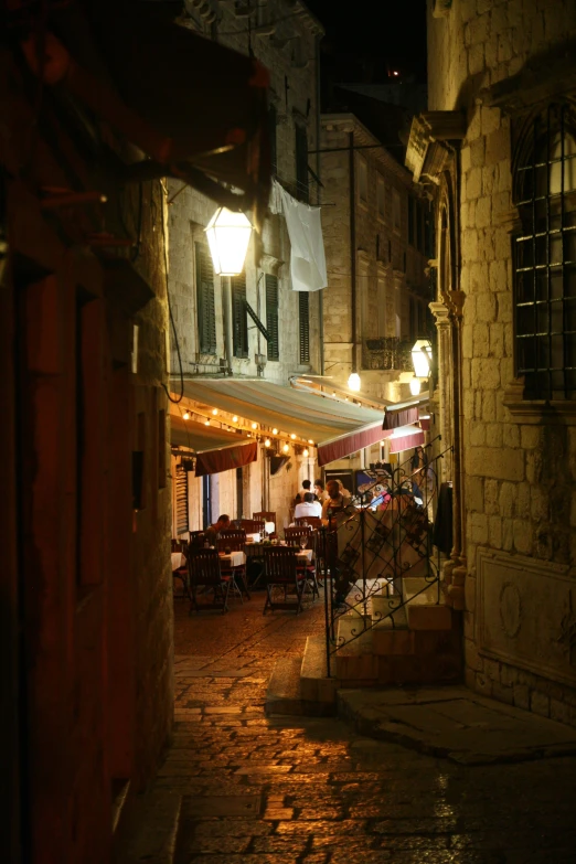 an alley with tables and chairs along side some buildings