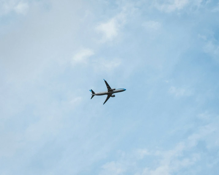 an airplane flies against the sky during a sunny day