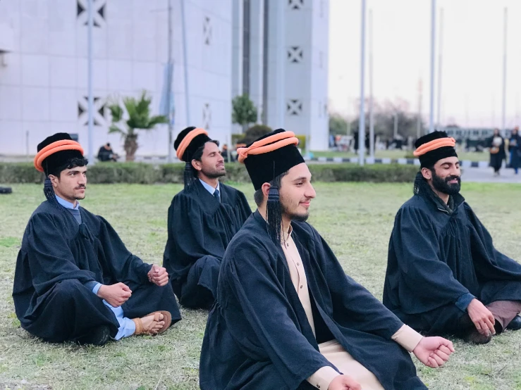 men in old black dress sitting in the grass