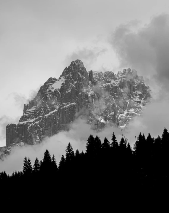 fog hangs over a mountain in black and white