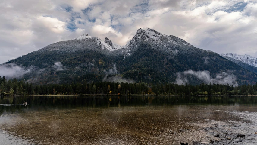 the mountains are covered in snow above the still water