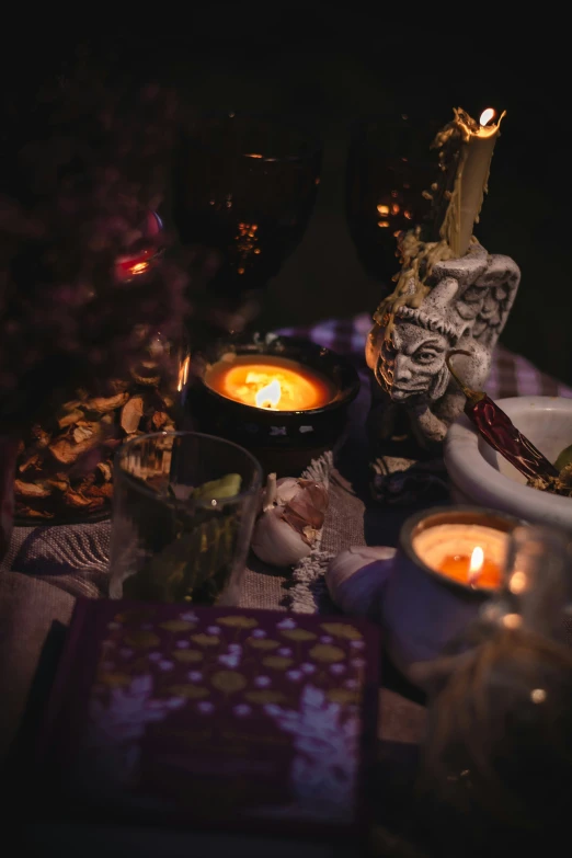 candle on the table surrounded by glasses and dishes