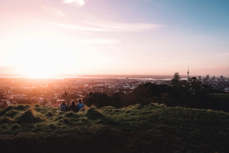 a couple of people are sitting on top of a hill