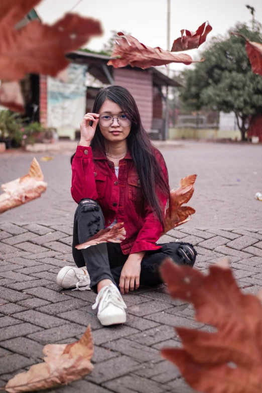 young woman sitting on the ground surrounded by leaves