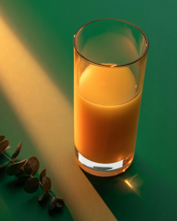 an orange is in a glass of juice on a green table