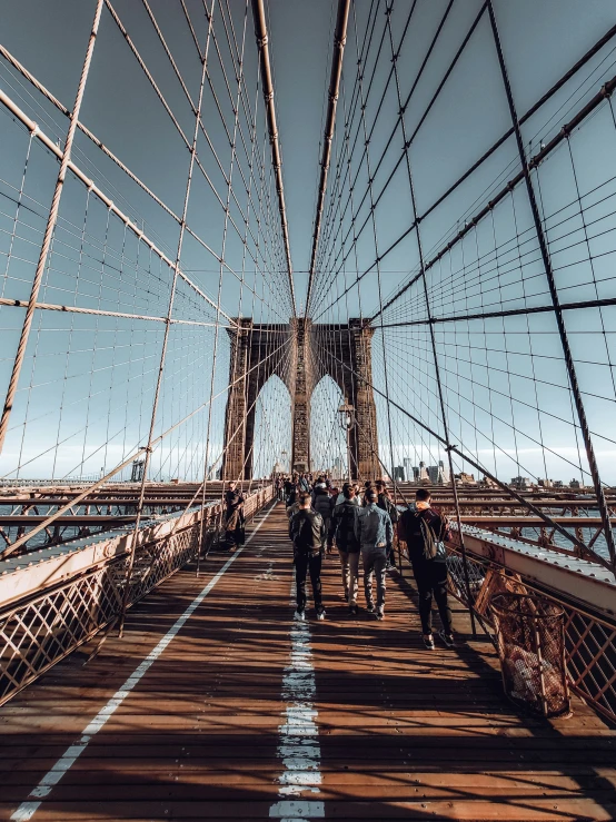 the people are crossing the suspension of a bridge