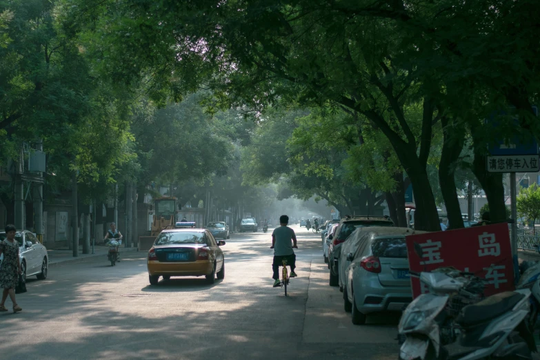 a man riding a bicycle down a road next to cars