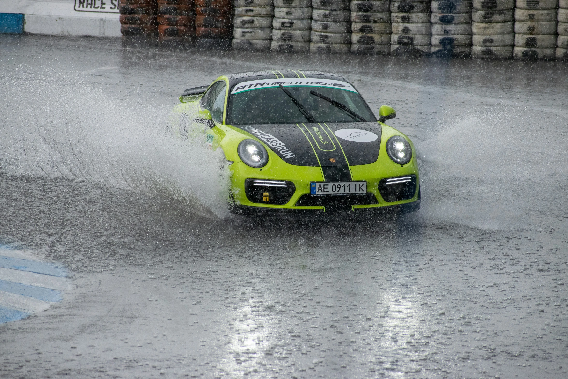 a green sports car driving on a rainy day