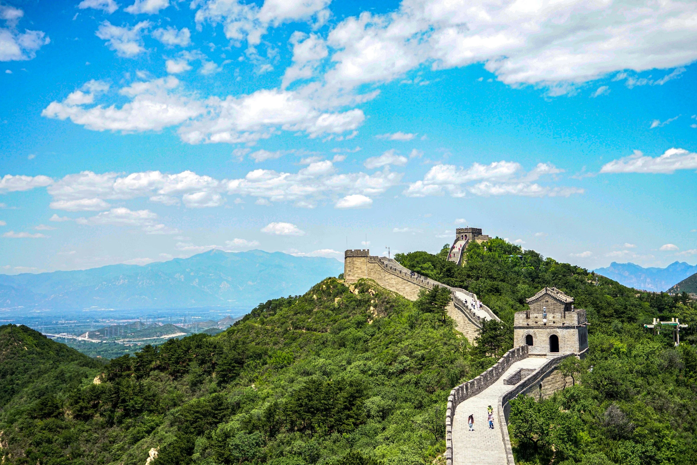 people walking up the great wall at the top of the cliff