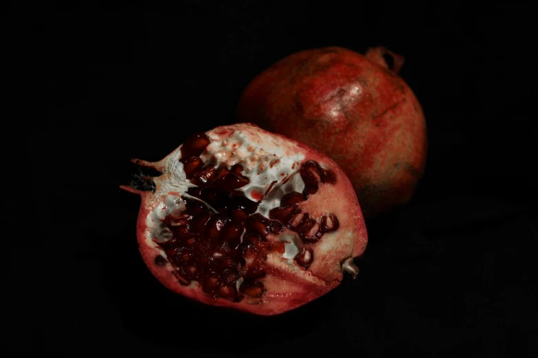 one half eaten pomegranate with seeds and one half peeled open